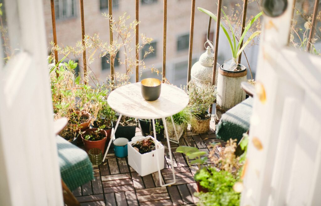Klein tafeltje op balkon met klein potje erop en omringt door planten en plantenpotjes